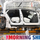 A photo of an electric car being assembled by robots at a factory.